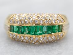 "Crafted from yellow gold, this stunning band is the perfect accessory for any occasion. Inset with deep-green emeralds and dazzling diamonds, it's a luxurious piece that will draw all eyes. Its timeless design and quality craftsmanship will make it a cherished addition to any jewelry collection. Metal: 18K Yellow Gold Gem: 10 Emeralds  Accents: 72 Diamonds totaling .50 Carats, SI in Clarity, H in Color Width of Band: 10.0 mm Height off Finger: 4.0 mm Ring Size: 8 Marks: \"18K\" Stamped on the i Emerald And Diamond Band, Gold Emerald Ring, Emerald Ring Gold, Anniversary Bands, Diamond Band, Emerald Ring, Gold Band, Deep Green, Pearl Pendant