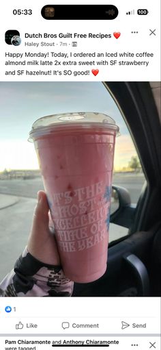 someone holding up a pink drink in their car