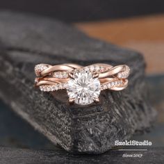 a rose gold engagement ring set with a round diamond in the center, on top of a rock