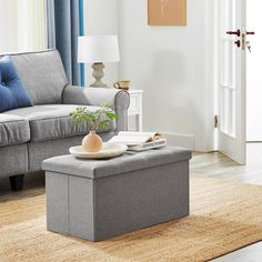 a living room with a couch, coffee table and books on the floor in front of it