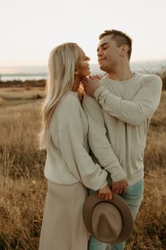 a man and woman are standing together in the grass, looking at eachother's face