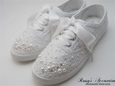 a pair of white shoes with pearls on the bottom and bows at the top,