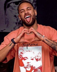 a man making a heart sign with his hands while wearing an orange t - shirt