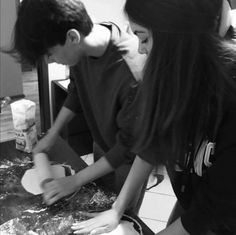 two people are making dough on a table