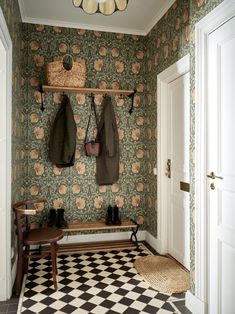 the entryway is decorated with vintage wallpaper and coat racks, as well as an antique bench