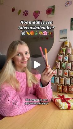 a girl in pink sweater holding up a carrot next to a box with chocolates on it