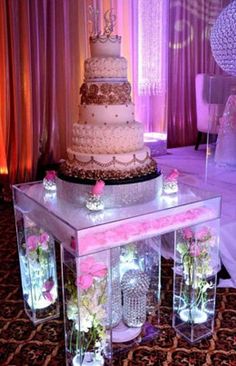 a wedding cake sitting on top of a table with vases and flowers in front of it