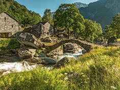 an old stone house sits next to a stream in the middle of a mountain valley