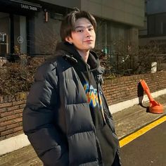 a young man standing on the side of a road next to a street sign and building