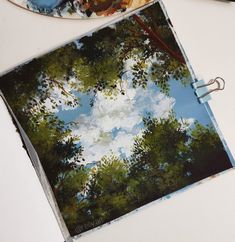 two plates with trees painted on them sitting on a table next to scissors and paintbrushes