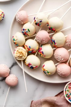 cake pops with sprinkles are on a plate next to other dessert items