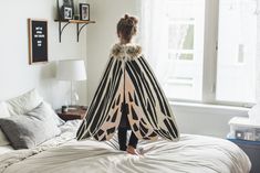 a woman standing on top of a bed with a zebra print blanket over her head