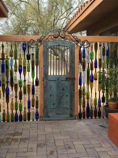 a wooden gate with glass bottles hanging from it's sides and a green door