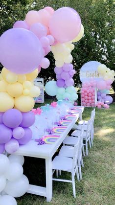 a table topped with lots of balloons next to a white table covered in pink and yellow