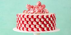 there is a red and white cake with candy canes on the top, sitting on a pedestal