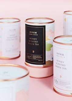 three tins of tea sitting on top of a pink table next to each other