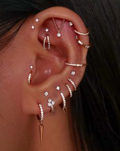 a woman's ear with several different piercings on her left side, including an arrow