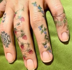 a woman's hand with tattoos on her left and right fingers, sitting on a green towel