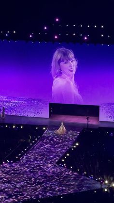 the stage is lit up with purple lights and a woman in white dress on it