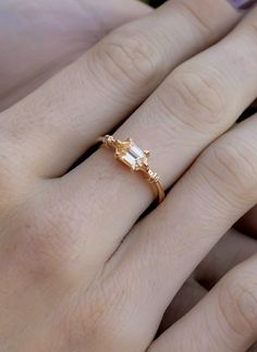 a woman's hand wearing a gold ring with an oval shaped diamond in the middle