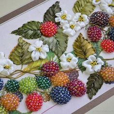 some fruit and flowers are laying on a table top with bead work in the middle