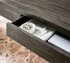 an open drawer with plates and utensils in it on a carpeted floor