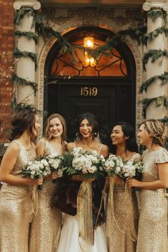 a group of women standing next to each other in front of a door holding bouquets