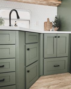 a kitchen with green cabinets and white counter tops