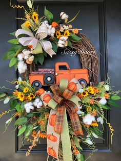 a wreath with an orange truck and sunflowers is hanging on the front door