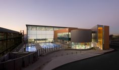 the building is lit up at night with lights on it's sides and an empty swimming pool in front