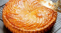 a cake sitting on top of a cooling rack next to a gold fork and knife