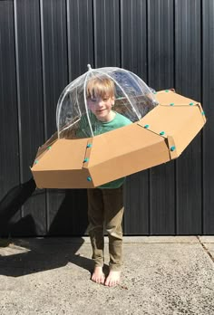 a young boy is holding an umbrella shaped like a spaceship