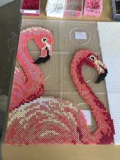 two pink flamingos sitting on top of a table next to other crafting supplies