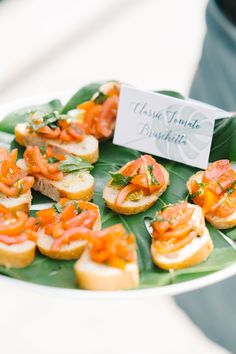 small appetizers are arranged on a leafy platter for guests to eat