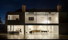 an illuminated house at night with large patio and dining room in the back ground area