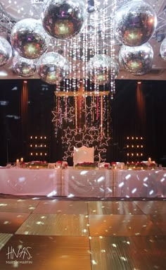 a dance floor with disco balls hanging from the ceiling and tables set up for an event