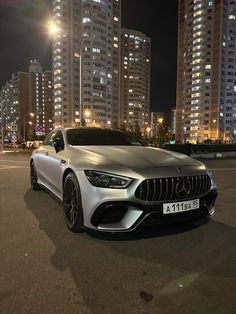 the mercedes amg coupe is parked in front of some tall buildings at night time