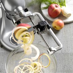 an apple slicer is being used to make spirals in a glass bowl on a table