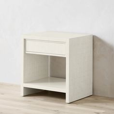 a white table with one drawer on the top and another shelf below it, against a wall