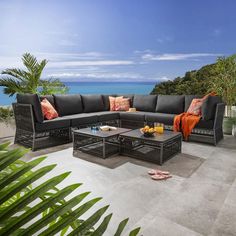 an outdoor living area with black wicker furniture and tropical plants on the patio overlooking the ocean