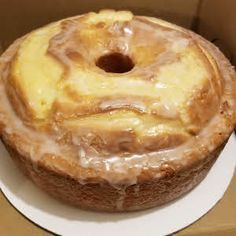 a glazed donut sitting on top of a white plate in a cardboard box,