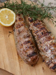 two grilled meats on a cutting board next to an orange and rosemary sprig