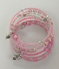 Pink Bead Leaf Memory Bracelet  The bracelet has been made with pink seed beads, silver seed beads, crystal glass beads, silver leaf beads, pale pink pearly beads and pale pink glass beads. The bracelet has been finished at each end with dangly beads. A statement piece that will add the finishing touch to any casual, work outfit or perfect for a dressy outfit, a lovely sparkling bracelet that will be a great addition to your jewellery collection. This bracelet measures 6cm in diameter.  This bracelet has been designed to give the appearance of individual bracelets stacked together but is one piece which wraps easily around your wrist. To wear a memory wire bracelet, starting with one end, you wrap the bracelet around your wrist. The brilliant thing about memory wire is its ability to retai Bohemian Pink Beaded Pearl Bracelet, Adjustable Pink Beaded Bracelet With Silver Beads, Adjustable Pink Pearl Bracelet With Spacer Beads, Pink Pearl Bracelet With Tiny Round Beads, Pink Bohemian Beaded Crystal Bracelet, Pink Multi-strand Bracelets With Colorful Beads, Pink Multi-strand Bracelet With Colorful Beads, Pink Multi-strand Colorful Beaded Bracelets, Pink Multi-strand Beaded Bracelets