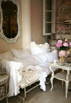 a white couch sitting next to a table with flowers on top of it in a living room