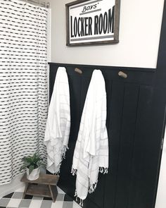 two white towels are hanging on the wall next to a black and white checkered floor