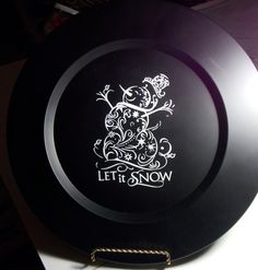 a black frisbee with the words let it snow printed on it and a gold chain