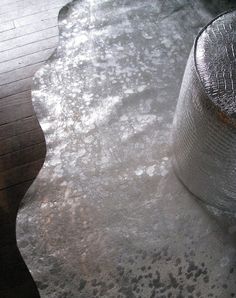 a metal object sitting on top of a wooden floor next to a water hose and trash can