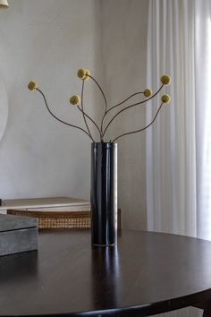 a vase with flowers on a table in front of a window