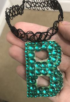 a hand holding a green beaded letter