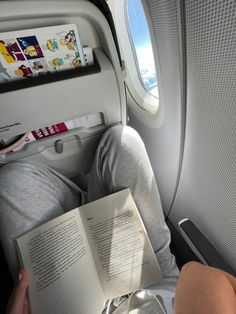 a person sitting in an airplane reading a book